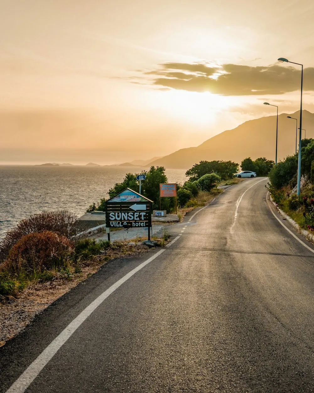 Gün batımında deniz kenarında kıvrılan sahil yolu
